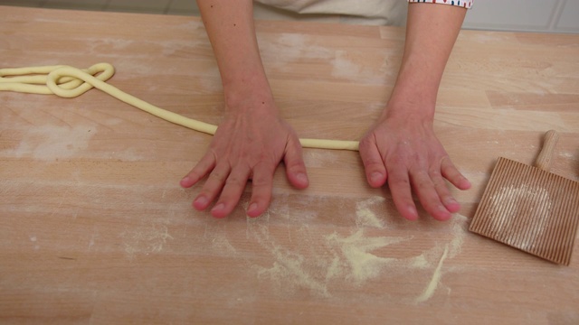 女人的手在厨房柜台上把面团揉成绳子视频素材