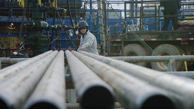 一个20多岁的年轻油田工人在一个寒冷的早晨在石油和天然气钻井平台上测量钻杆的慢动作镜头视频下载