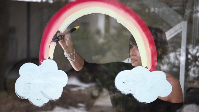 独自在家的妇女在走廊窗户上画Covid-19彩虹标志视频下载