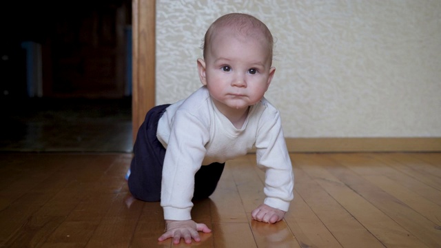 有趣的白人婴儿学会在家里的地板上用四肢爬行视频下载