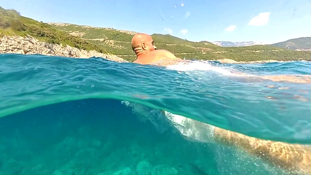 慢动作近距离水下:一个人从高岩石上跳入水中，一头扎进海里视频下载