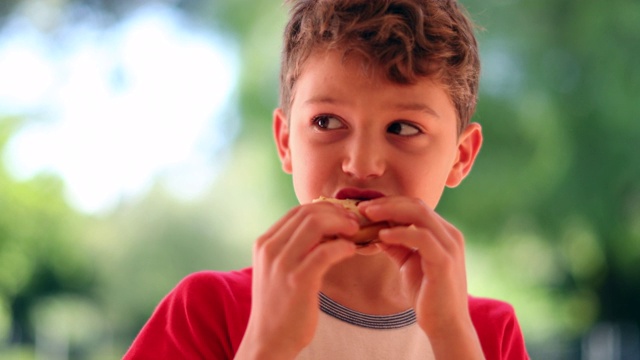 孩子在吃三明治，小男孩吃了一口视频素材