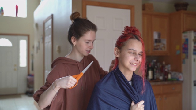 姐姐在家给妹妹剪头发，两人一起玩。视频素材