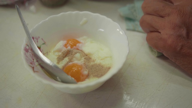 一位留着白色长发的亚洲老人正在餐桌上为家人准备煮熟的鸡蛋。视频素材