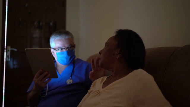 健康访视员和一位老年妇女家访-使用数字平板电脑视频素材