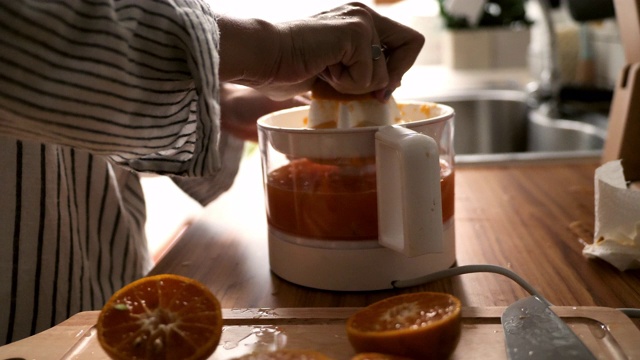 千禧一代亚洲妇女在早上做橙汁视频素材