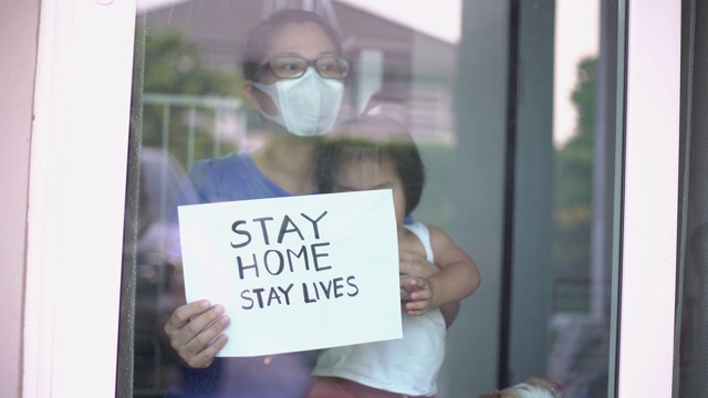 冠状病毒感染的情况下，母亲戴口罩，儿子在家里显示在家的标志，帮助拉平曲线视频下载
