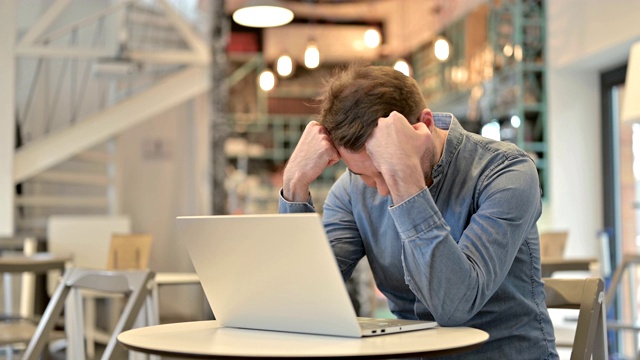 一个漫不经心的人在咖啡馆用笔记本电脑处理损失视频素材