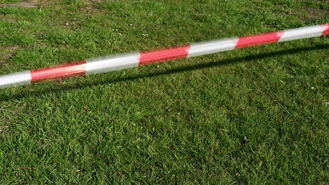 闭合:宽阔的白色和红色缎带在强风中在绿草上移动。德国。视频下载