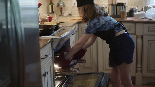 小女孩从烤箱里拿出刚烤好的草莓馅饼。视频素材
