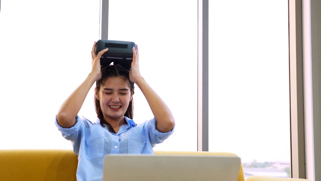 亚洲女性坐在和使用虚拟现实头盔在虚拟现实游戏。视频下载