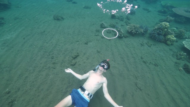 一个在水下学习如何制作气泡环的人。视频下载