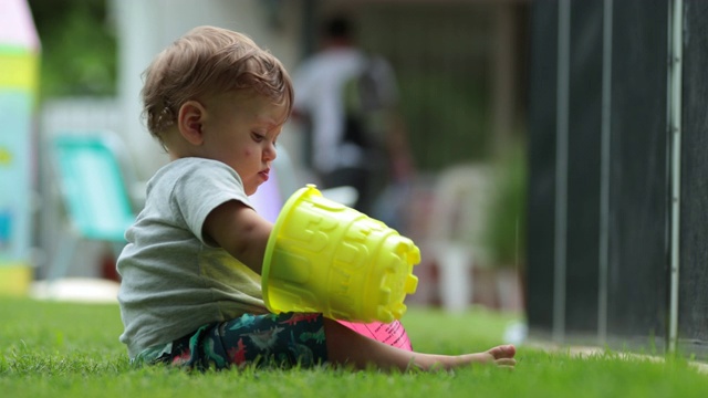 婴儿在后院玩水桶。婴幼儿检查桶视频素材