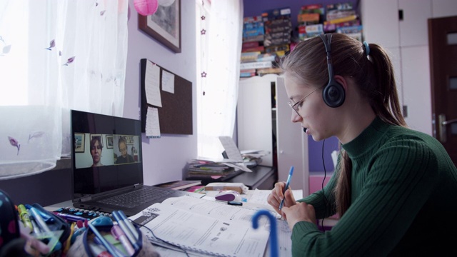 一个十几岁的女孩在她的房间里上在线课。视频素材
