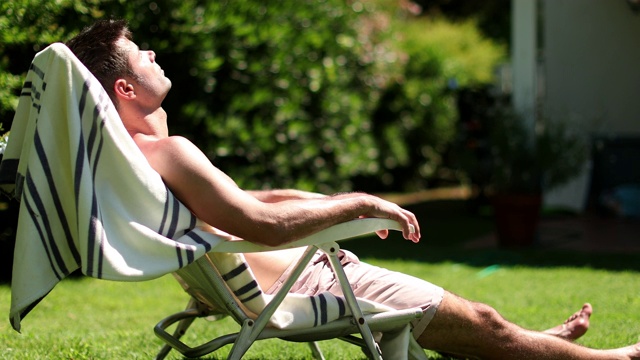 在自家草坪上晒太阳的男人。人在户外放松视频下载
