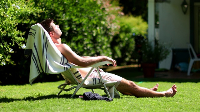 帅哥在后院晒日光浴。人在暑假放松视频下载