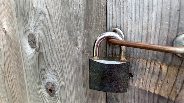 一只手摸着大金属锁上的挂锁，一扇紧闭的木门关上，私有财产保护概念视频素材