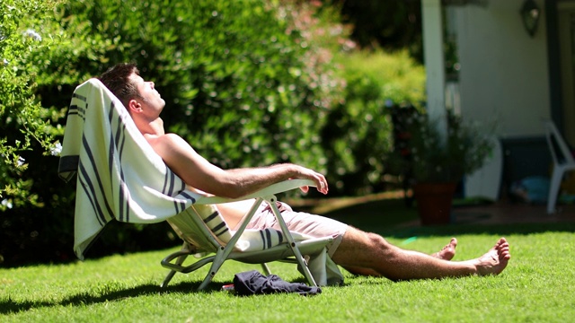 男人放松在家后院日光浴视频下载