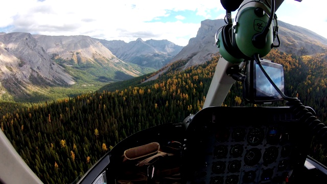 在落基山脉的秋天森林里驾驶直升机的飞行员视频下载