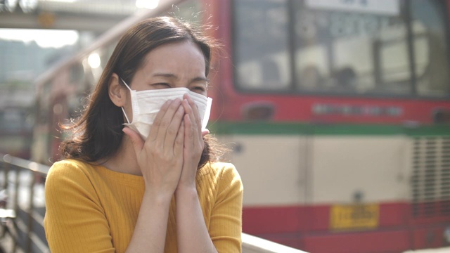 亚洲妇女咳嗽和生病的口罩在街头的城市户外视频素材