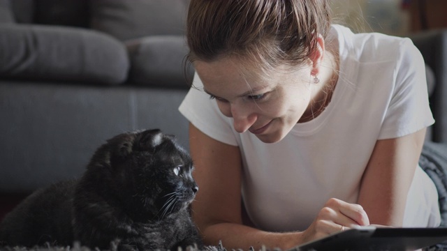 一位妇女在家里和她的宠物一起使用平板电脑视频素材