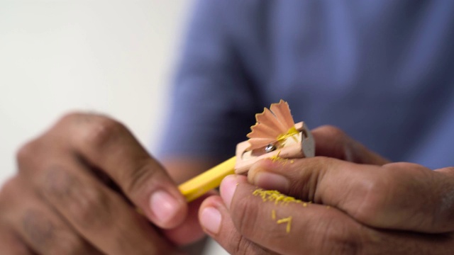 教育的概念。靠近男性的手正在用卷笔刀削黄色的铅笔。视频下载