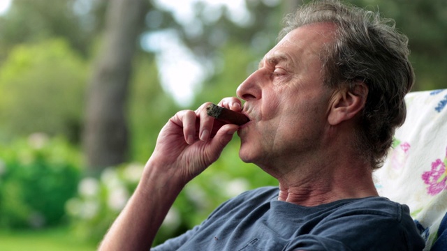 一位老人在户外抽雪茄享受退休生活视频素材