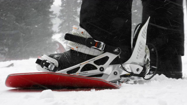 一个人把他或她的滑雪板扔到雪上的慢动作镜头，把他们的靴子脚进入绑定，剪绑定，和滑雪板远离埃尔多拉滑雪度假村附近的博尔德，科罗拉多州在一个下雪的，阴天的冬天视频下载