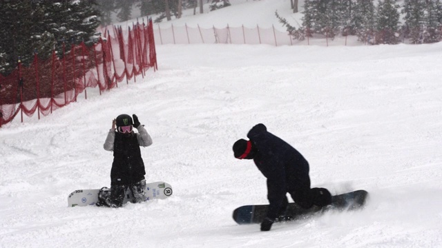慢动作拍摄的一个滑雪板嬉戏喷洒另一个滑雪板与雪视频素材