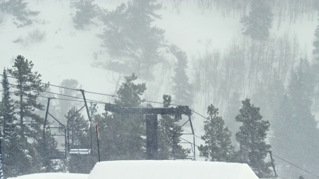 完整的冬季装备滑雪板完成一个“背部Rodeo 720鼻子抓取”的技巧与森林和滑雪跳跃在背景在科罗拉多州博尔德附近的埃尔多拉滑雪度假村雪天，阴天视频素材
