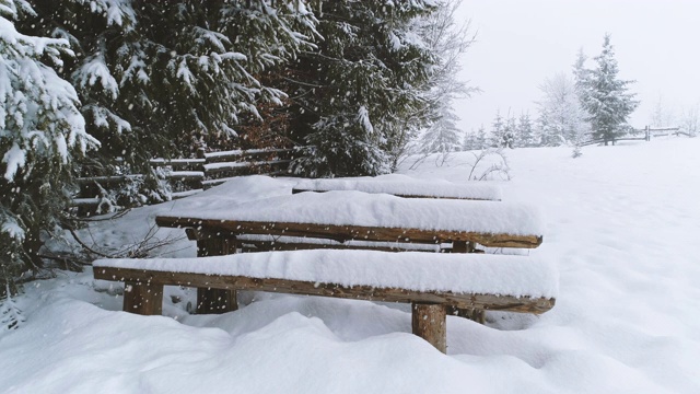 长凳被雪覆盖，而更多的雪落下来视频下载