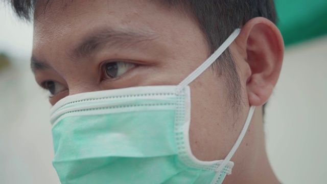 近距离的亚洲年轻男子戴着口罩。视频素材