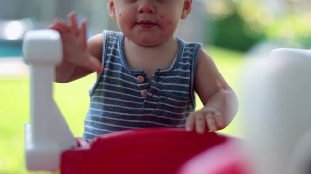 在夏天的院子里，可爱的蹒跚学步的婴儿。婴儿脸上满是蚊虫叮咬视频下载