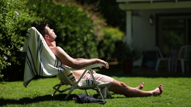 男人在后院休息日光浴。正在户外小憩的人视频下载