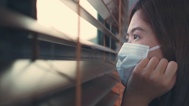 一名亚洲女性正在通过窗口进行自我隔离视频素材