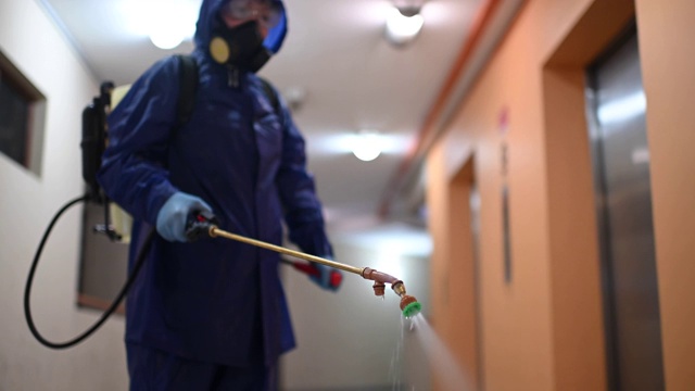一名身着防护服的女子在走廊喷洒和消毒灭虫剂视频下载