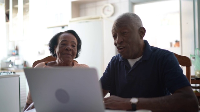 一对老年夫妇在厨房使用笔记本电脑视频素材