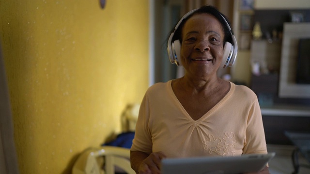 老年妇女在家边走边用平板电脑听音乐视频素材