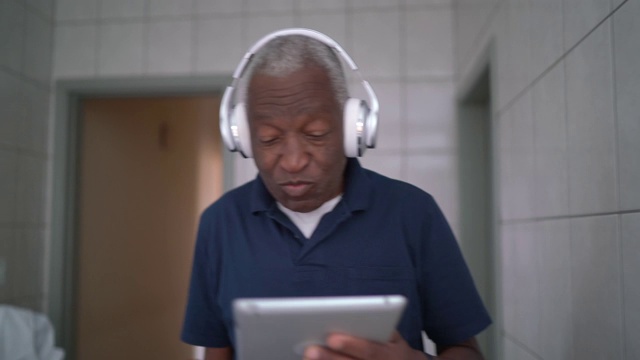 老人走路和听音乐的数字平板电脑在家视频素材