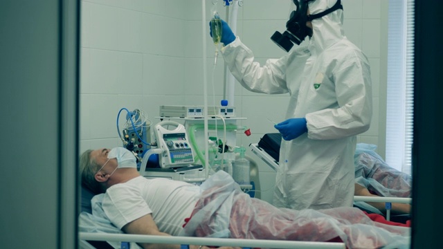 冠状病毒大流行，2019-ncov，冠状病毒的概念。穿着防护服的医务人员正在给病人进行静脉注射视频素材