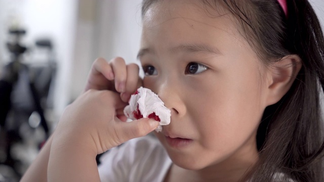 一个小女孩的特写，用纸巾擦鼻子流血视频素材