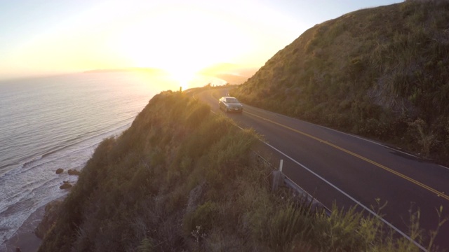 一辆摩托车在海岸高速公路上行驶，夕阳西下视频素材
