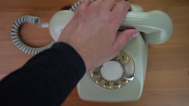 一只手捡起并挂起一台古董白/绿电话。视频素材