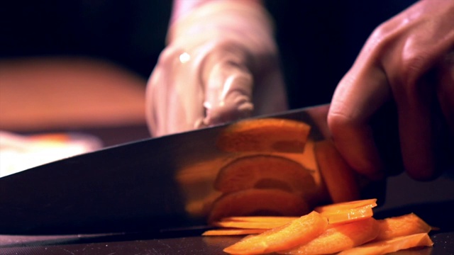 人手戴手套切菜在砧板上用刀切胡萝卜的精准技巧视频素材