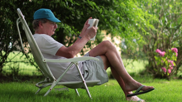 退休老人在户外看书。老人在读小说故事视频素材