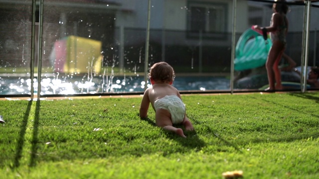 婴儿观察孩子们在游泳池玩耍，蹒跚学步的孩子在后院的草坪上玩耍视频素材