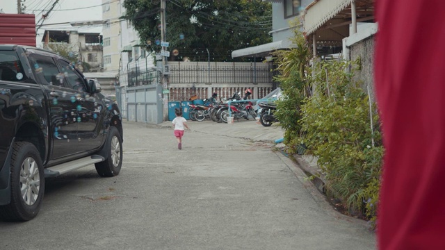 一个年轻的亚洲女孩追逐着她父亲吹出的肥皂泡。视频素材