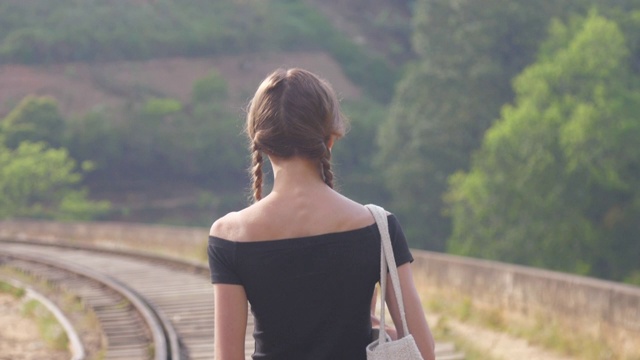 女孩在黑色上衣步行到铁路在自然中近距离视频下载