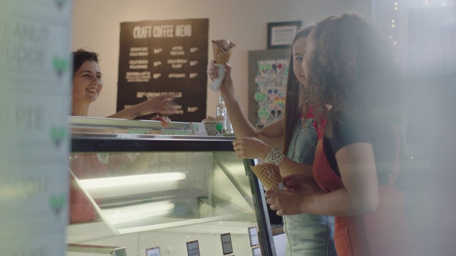 冰淇淋店的店员给两个小女孩一个冰淇淋视频素材