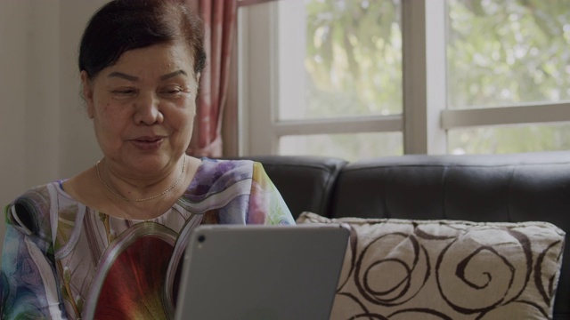 4k分辨率手持式拍摄亚洲高级妇女在冠状病毒封锁情况下，手持平板设备与孙女进行视频通话或视频会议技术交谈。视频素材
